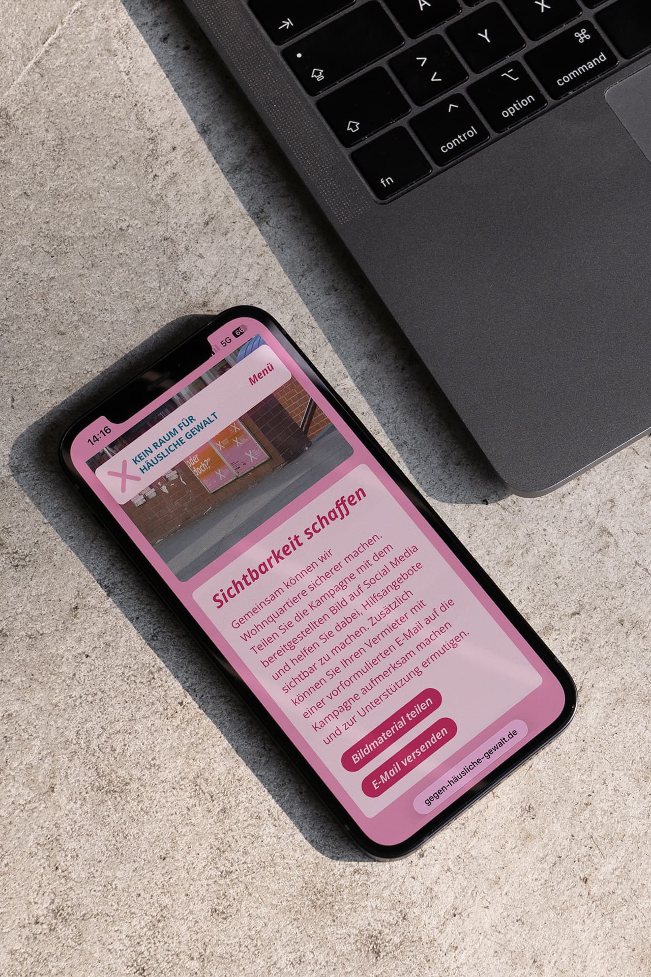Ein iPhone liegt auf einem Untergrund auf Stein. Auf dem Display ist die Webseite der Kampagne "Kein Raum für häusliche Gewalt" geöffnet.