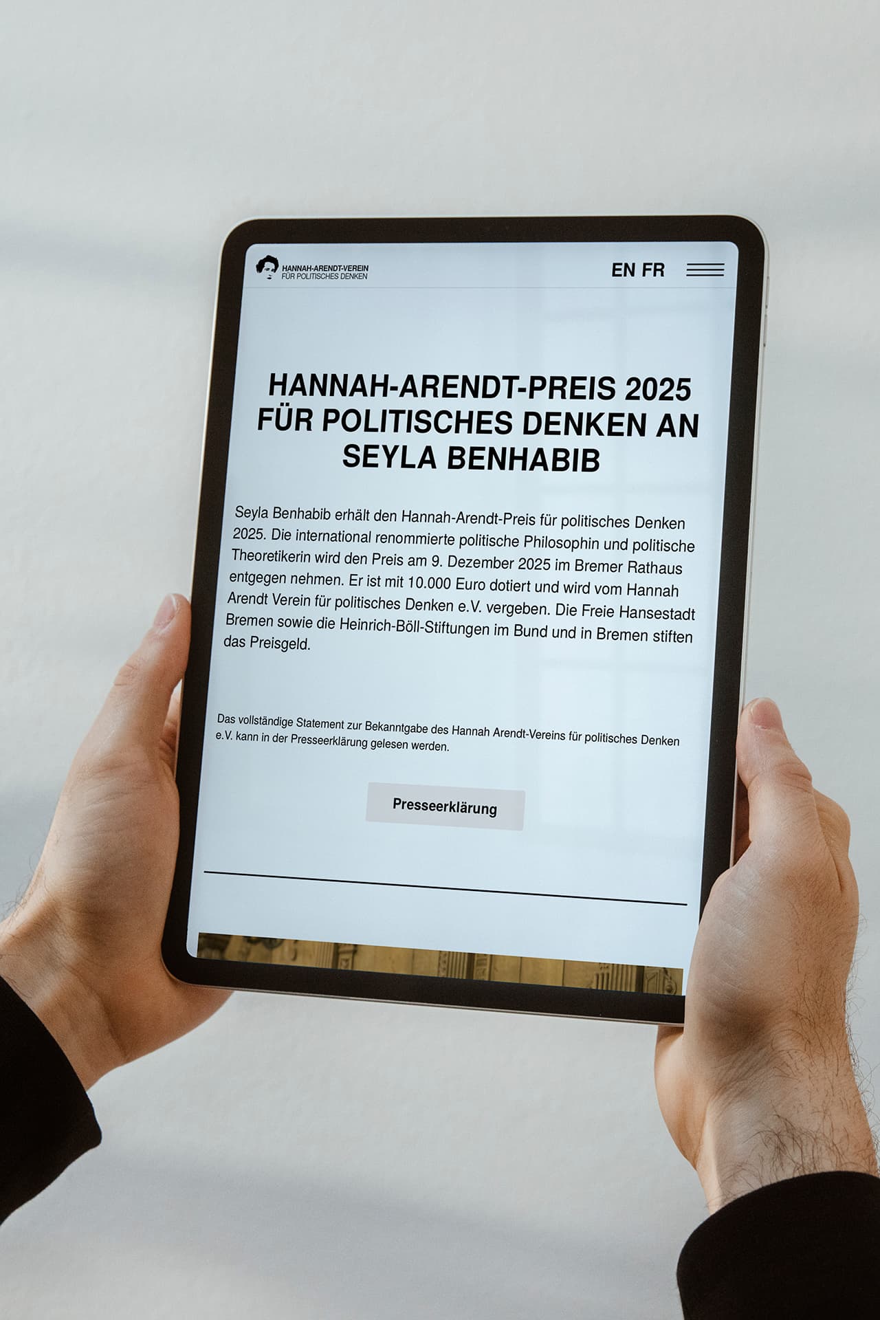 Ein Tablet wird in beiden Händen gehalten. Auf dem Bildschirm sieht man die Webseite des Hannah-Arendt-Preises.